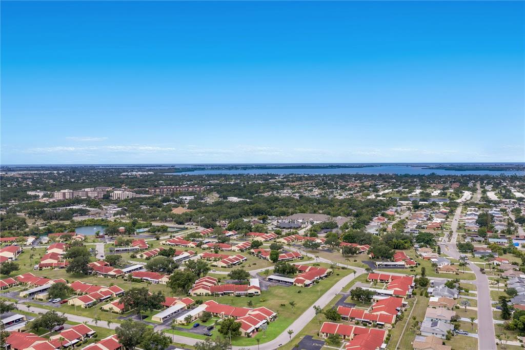 An aerial view shows a residential neighborhood with many single-story buildings featuring red roofs — 1208 56TH STREET W UNIT 1208, BRADENTON, FL