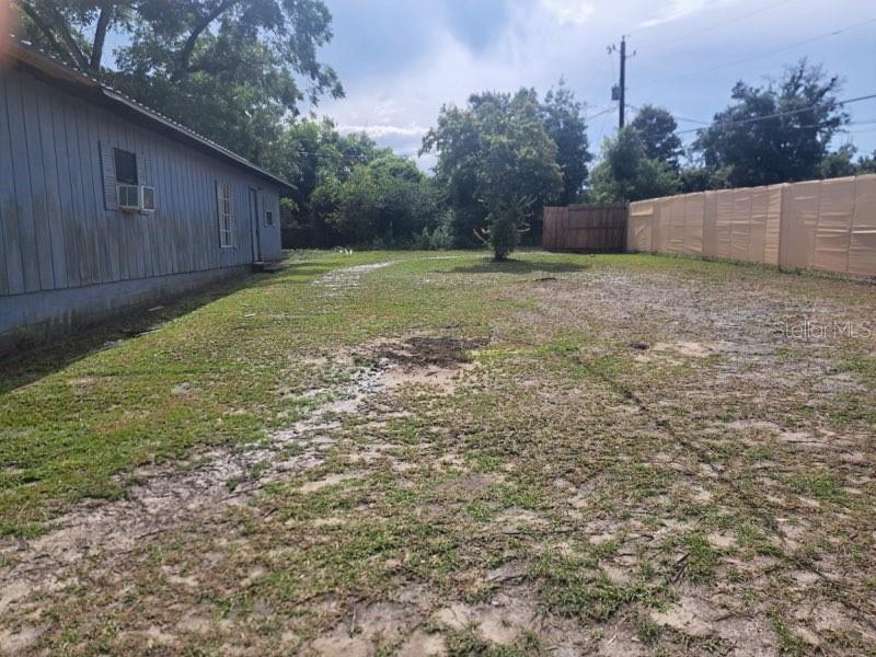 A side view of a house with blue siding and a large, partially grassed backyard — 4381 LEE ROAD, MARIANNA, FL