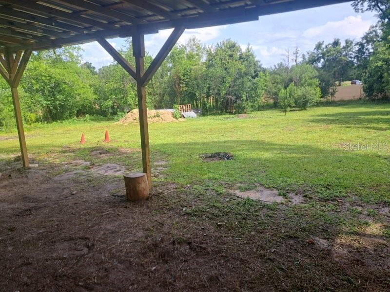 A view from under a covered patio looking out onto a large, grassy backyard — 4381 LEE ROAD, MARIANNA, FL