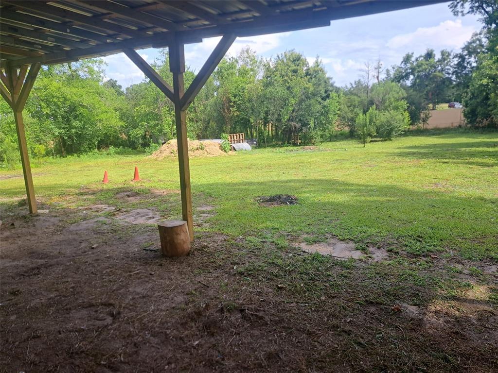A view from under a wooden patio cover looking out onto a grassy backyard — 4381 LEE ROAD, MARIANNA, FL