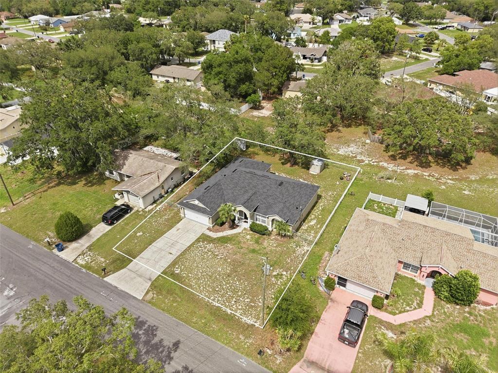An aerial view shows a single-story house with a dark roof and a concrete driveway — 10487 BRADFORD STREET, SPRING HILL, FL