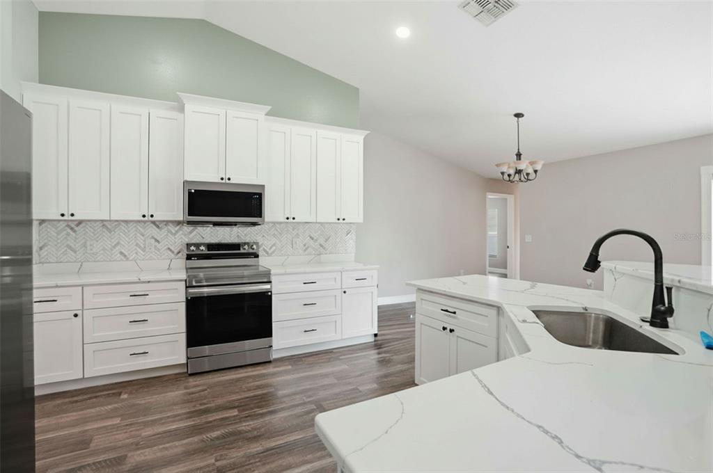 A kitchen with white cabinets, stainless steel appliances, and a white marble-look island countertop — 10487 BRADFORD STREET, SPRING HILL, FL