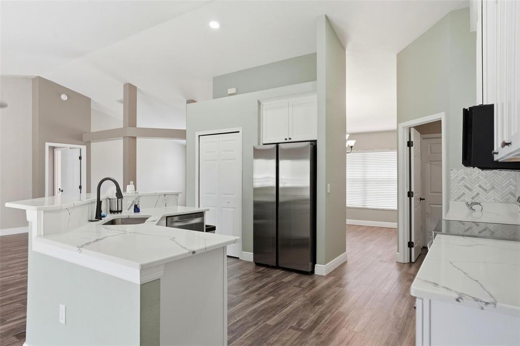 A kitchen features white marble-look countertops, stainless steel appliances, and light green walls — 10487 BRADFORD STREET, SPRING HILL, FL