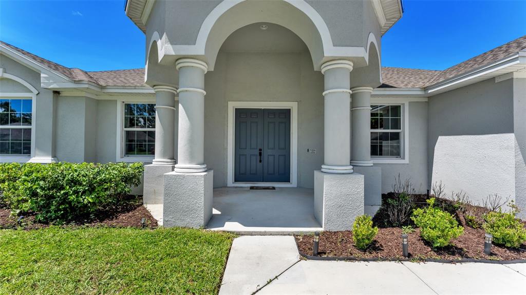 The exterior of a house features a covered entryway with two columns and double doors — 283 COVE AT EAGLE LAKE CIRCLE, EAGLE LAKE, FL