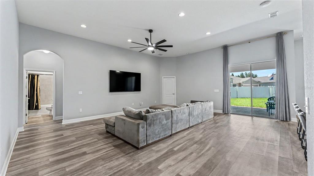 A living room features gray walls, wood-look flooring, a sectional sofa, and a sliding glass door — 283 COVE AT EAGLE LAKE CIRCLE, EAGLE LAKE, FL