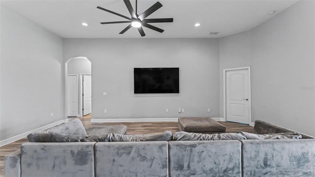 A living room features a large gray sectional sofa, a wall-mounted television, and a ceiling fan — 283 COVE AT EAGLE LAKE CIRCLE, EAGLE LAKE, FL