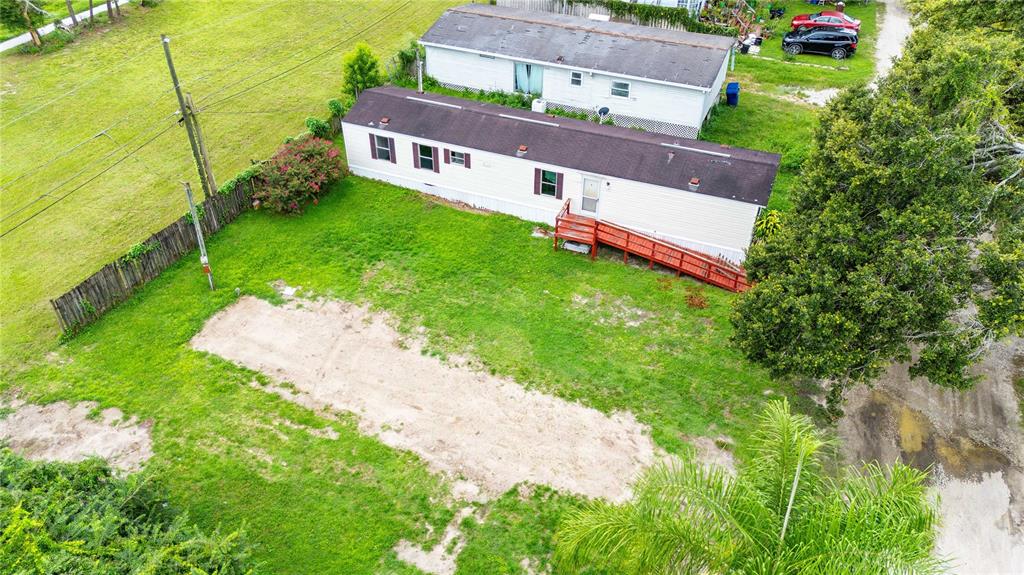 An aerial view shows a mobile home with a red wooden ramp on a grassy lot — 39140 ORIENT AVENUE, ZEPHYRHILLS, FL