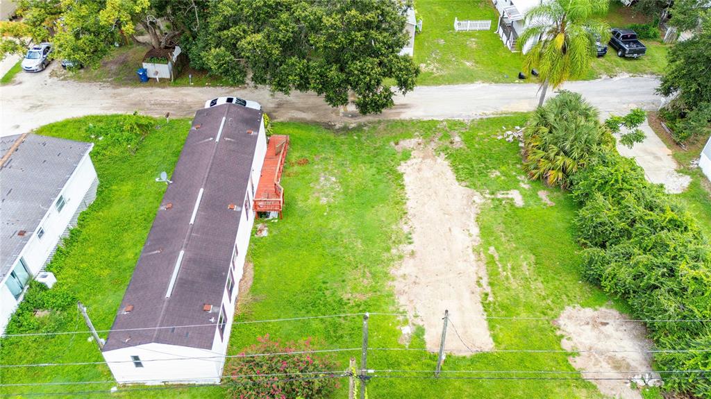 An aerial view shows a mobile home with a deck next to a vacant lot — 39140 ORIENT AVENUE, ZEPHYRHILLS, FL
