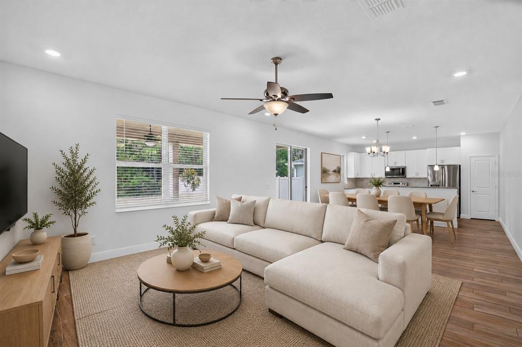 A living room with a beige sectional sofa, coffee table, and an open-concept kitchen beyond — 16420 WINDING PRESERVE CIRCLE, CLERMONT, FL