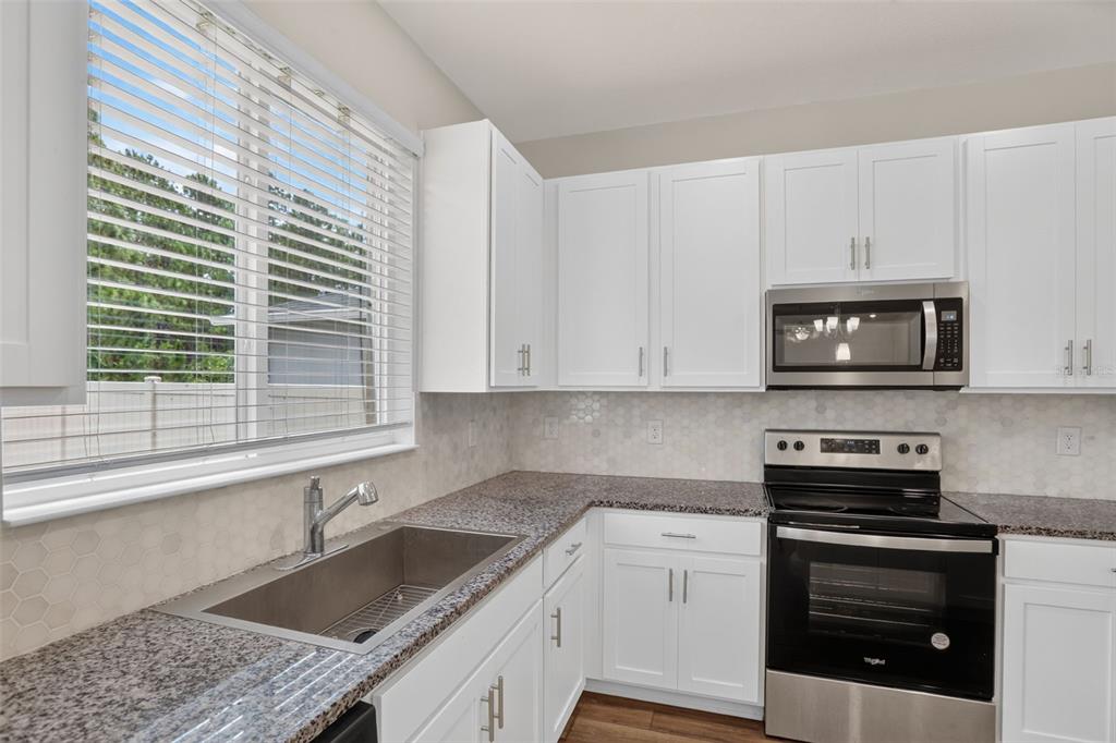 A kitchen with white cabinets, granite countertops, a stainless steel sink, and stainless steel appliances — 16420 WINDING PRESERVE CIRCLE, CLERMONT, FL