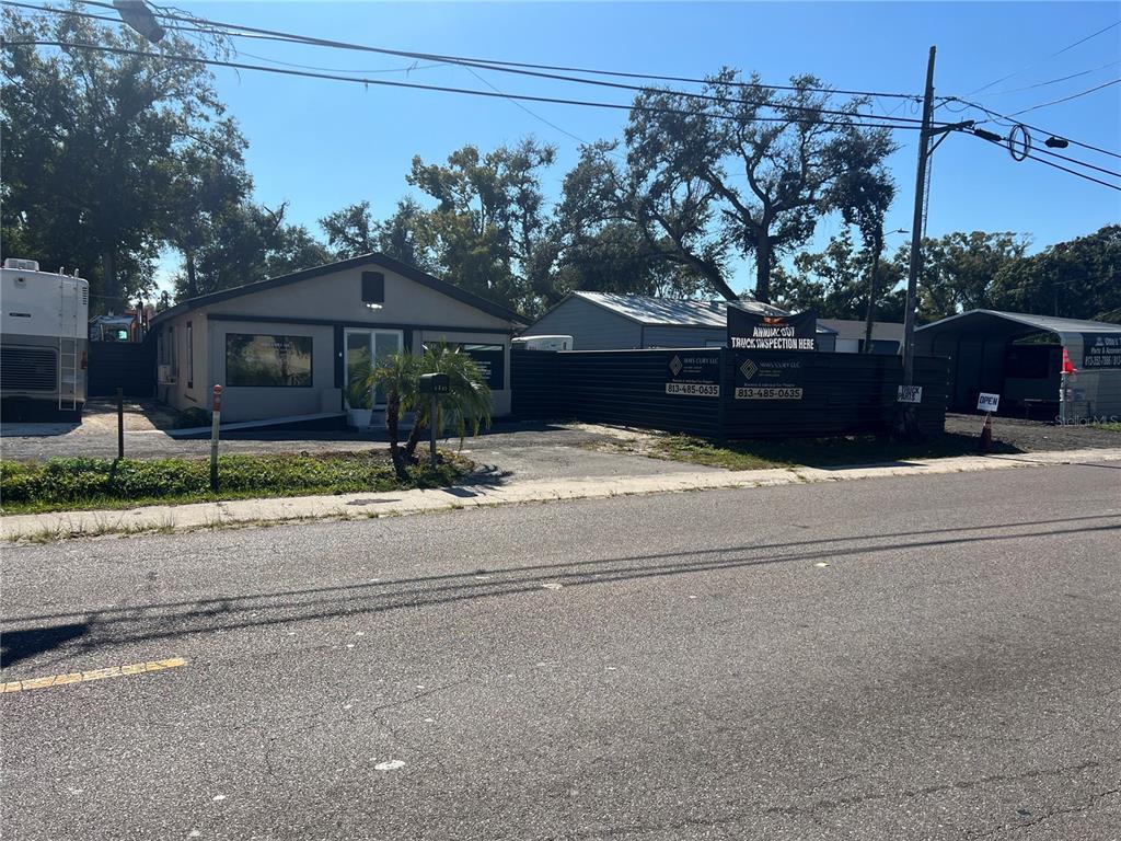 A single-story commercial building with a fenced lot and a sign advertising truck inspections — 5827 E COLUMBUS DRIVE, TAMPA, FL