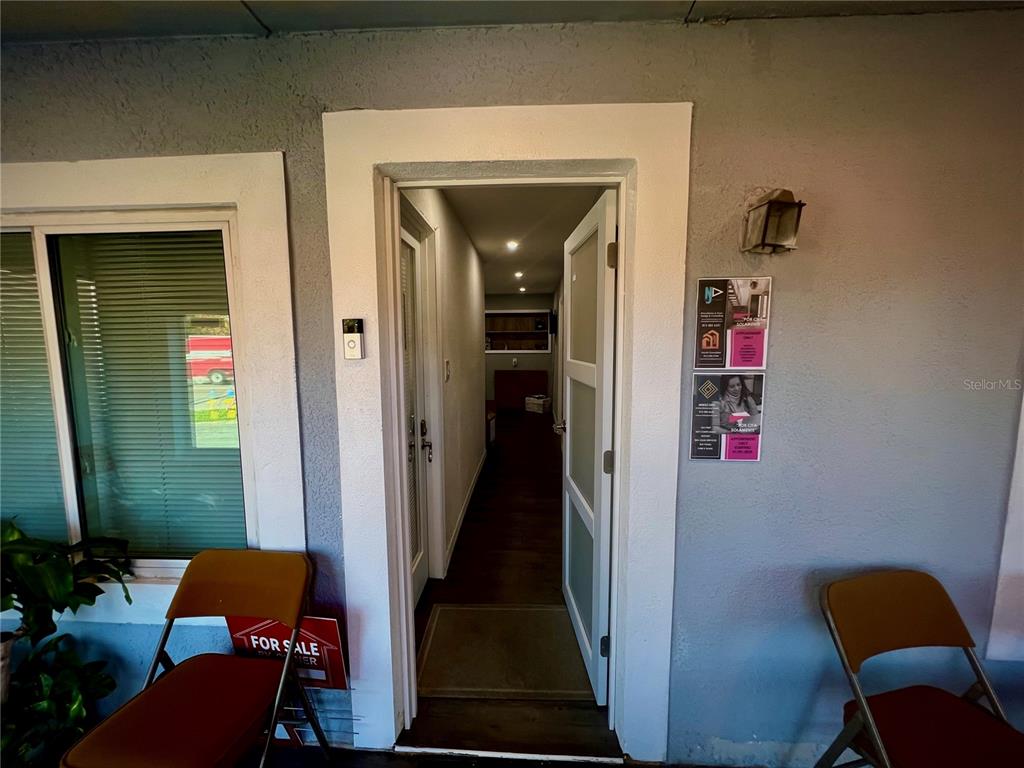 An open doorway leads into a narrow interior hallway from a covered porch area — 5827 E COLUMBUS DRIVE, TAMPA, FL