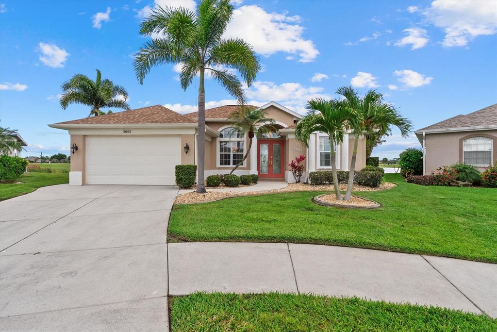 A single-story house with a two-car garage, palm trees, and a concrete driveway — 5665 RIVIERA COURT, NORTH PORT, FL