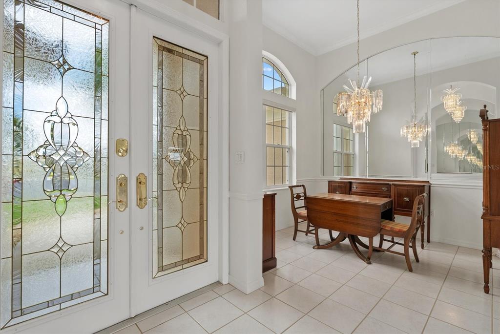 A dining area features a wooden table, chairs, a chandelier, and a large wall mirror — 5665 RIVIERA COURT, NORTH PORT, FL