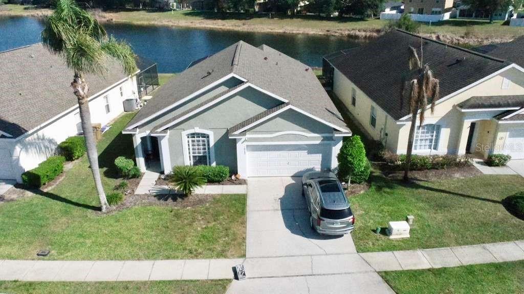 An aerial view shows a single-story house with a two-car garage and a backyard pond — 16732 GLENBROOK BOULEVARD, CLERMONT, FL
