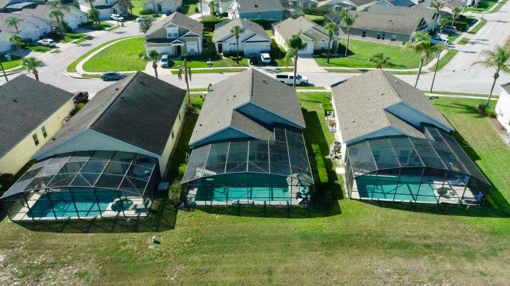 An aerial view shows three suburban houses with screened-in swimming pools in their backyards — 16732 GLENBROOK BOULEVARD, CLERMONT, FL