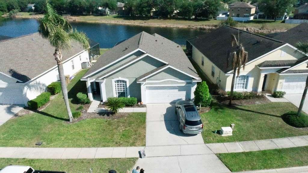 An aerial view shows a single-story house with a two-car garage and a backyard pond — 16732 GLENBROOK BOULEVARD, CLERMONT, FL