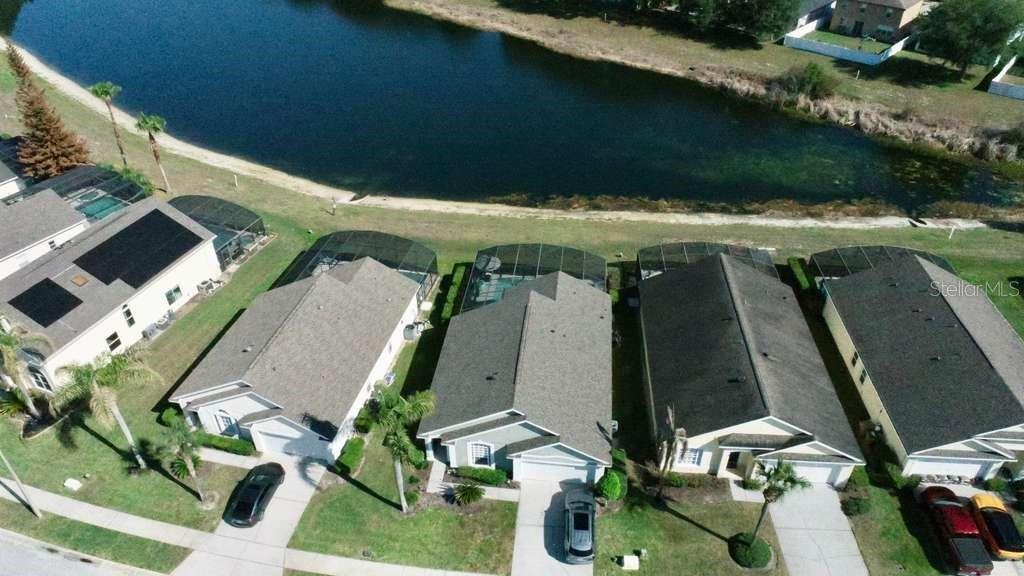 An aerial view shows several suburban houses with screened-in pools backing onto a pond — 16732 GLENBROOK BOULEVARD, CLERMONT, FL