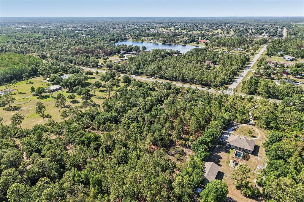 An aerial view shows a house with a pool surrounded by dense woods and roads — OBERLY PARKWAY, ORLANDO, FL