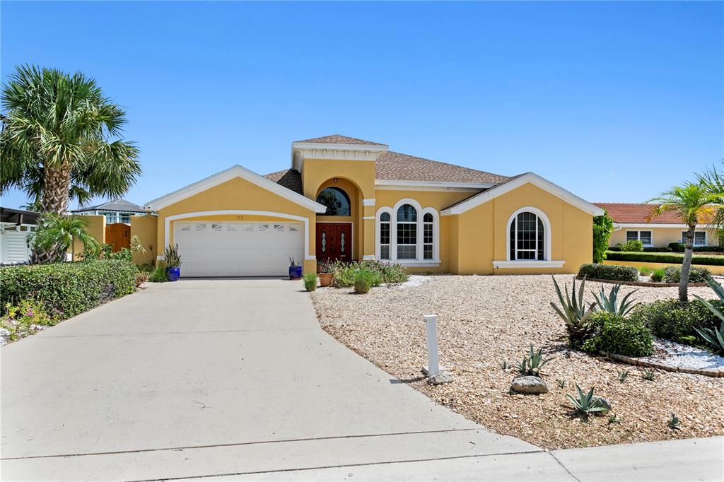 A yellow single-story house with a two-car garage and a gravel front yard — 115 ALETA DRIVE, BELLEAIR BEACH, FL