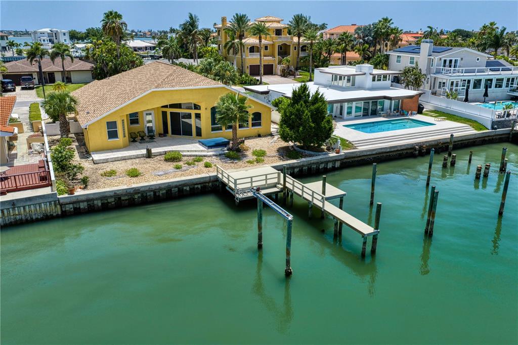 An aerial view of a yellow waterfront house with a private dock and swimming pool — 115 ALETA DRIVE, BELLEAIR BEACH, FL