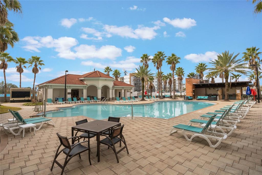 A swimming pool surrounded by lounge chairs, a patio dining set, and palm trees — 7395 UNIVERSAL BOULEVARD UNIT 906, ORLANDO, FL