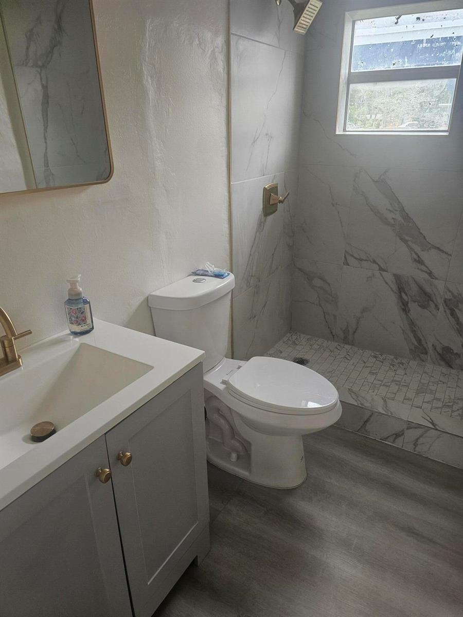 A bathroom features a gray vanity, a white toilet, and a tiled walk-in shower — 505 NW 16th Avenue, Pompano Beach FL 33069, POMPANO BEACH, FL