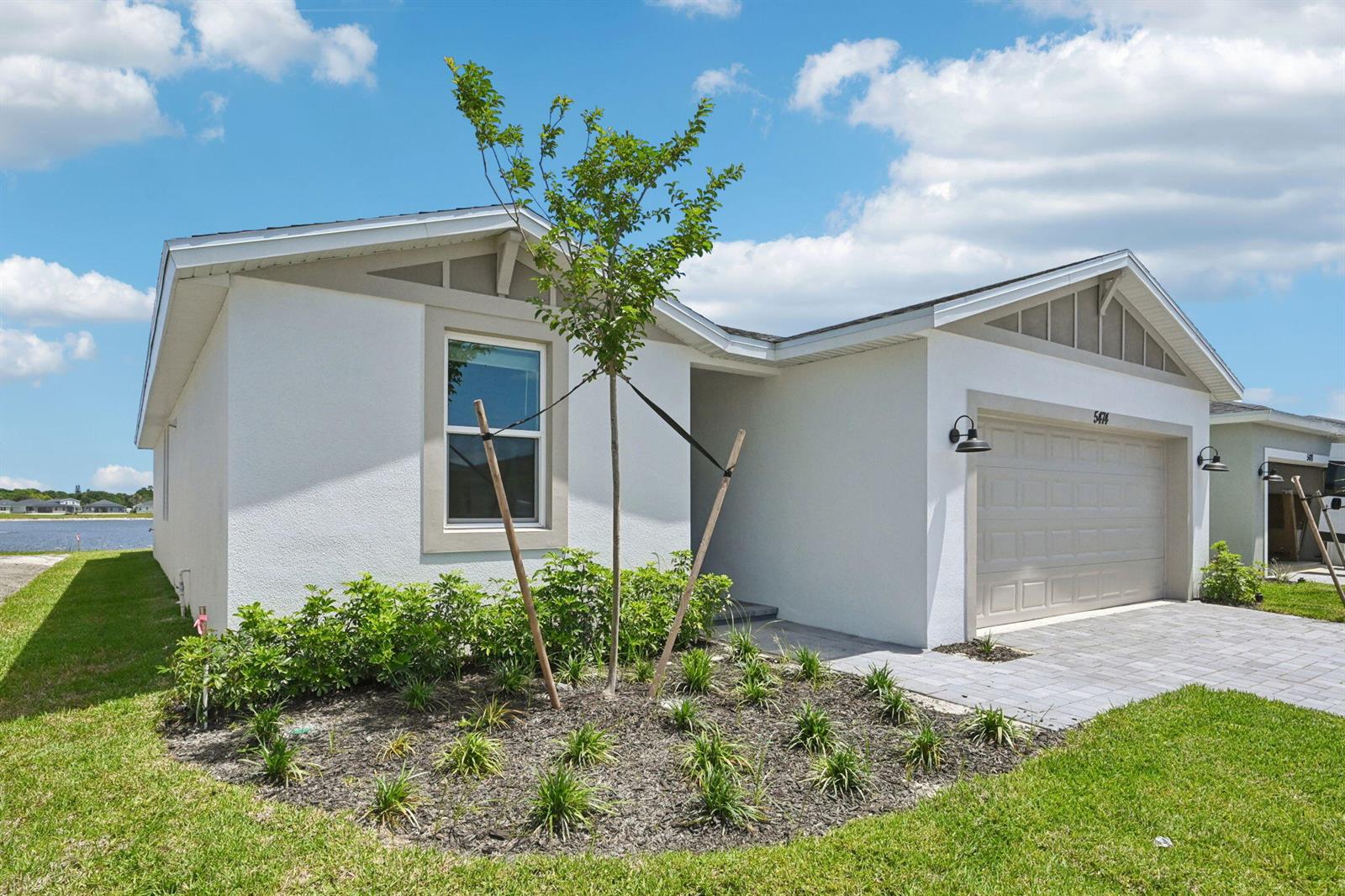 A single-story house with white stucco siding, a two-car garage, and a landscaped front yard — 5474 Hampton Park Circle, Vero Beach FL 32966, VERO BEACH, FL