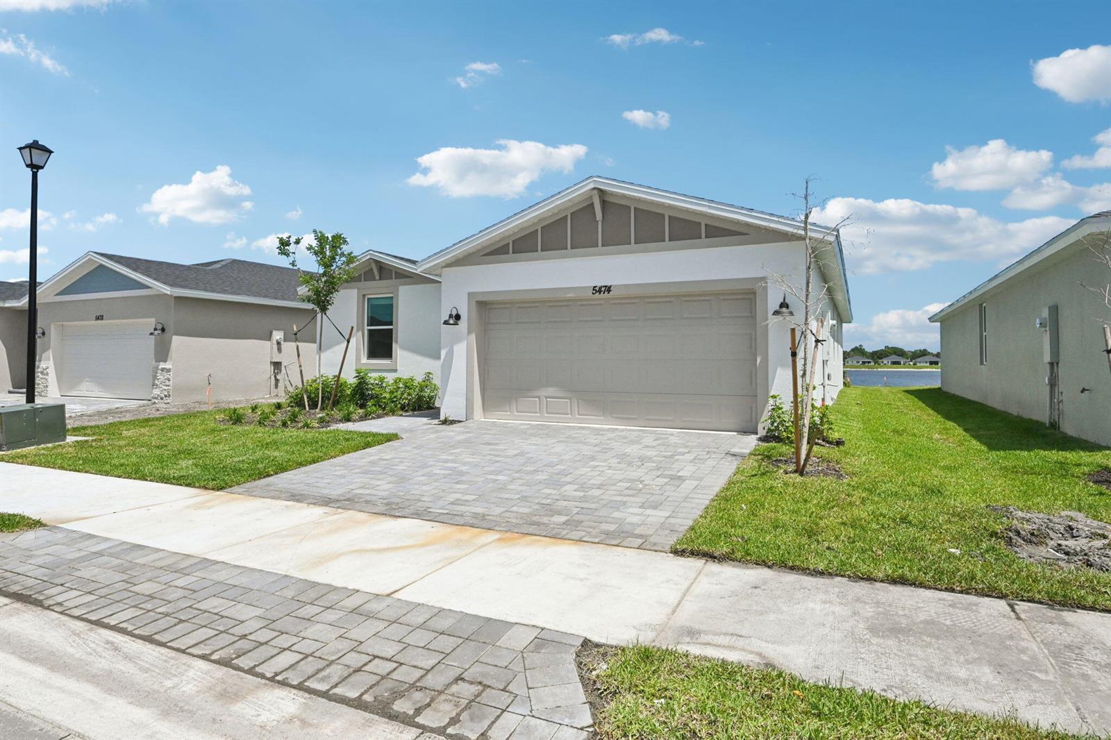 A single-story house with a white exterior, a two-car garage, and a paved driveway — 5474 Hampton Park Circle, Vero Beach FL 32966, VERO BEACH, FL