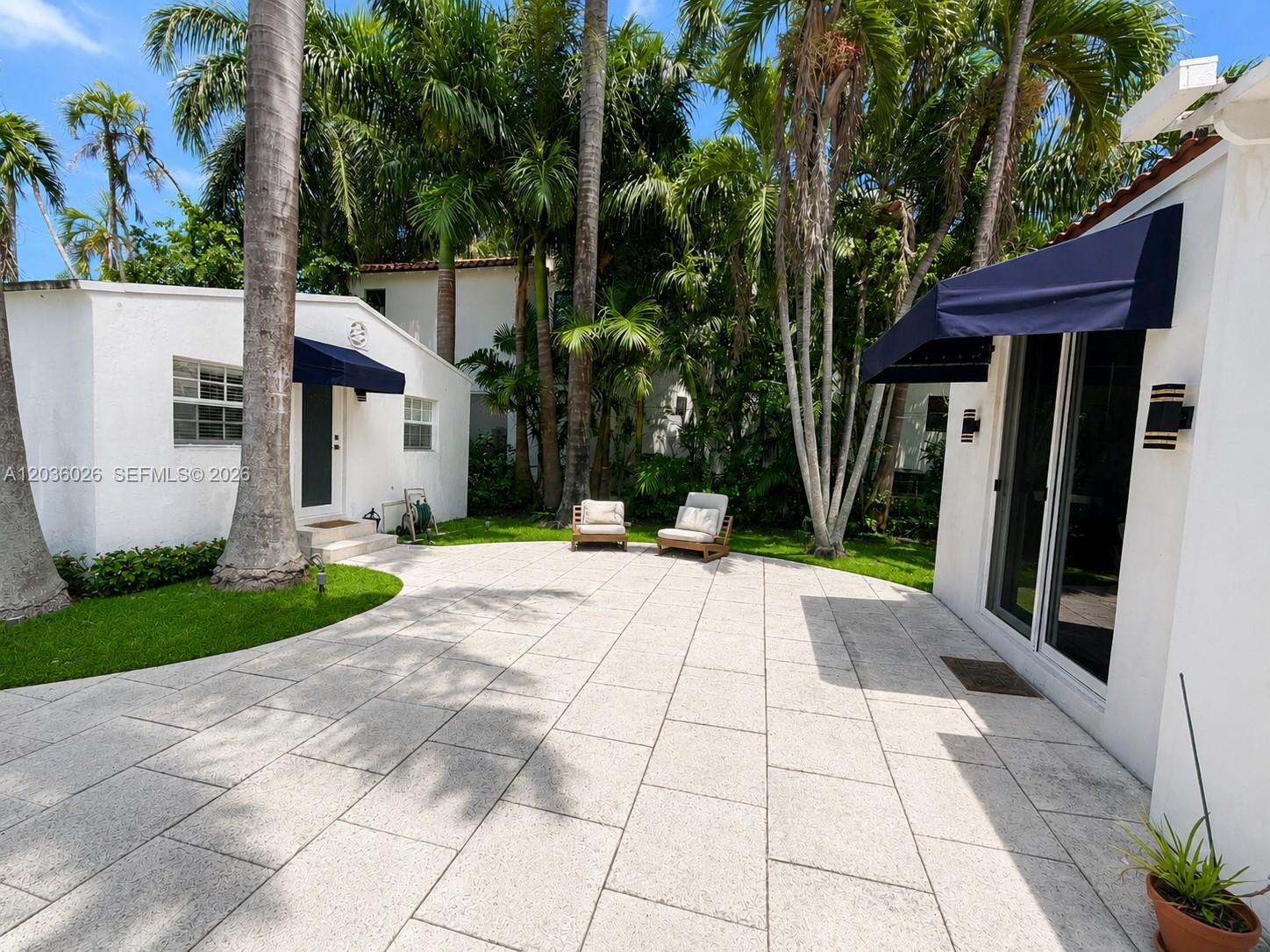 A paved patio sits between two white buildings surrounded by lush palm trees — 265-A Palm Ave, Miami Beach FL 33139, MIAMI BEACH, FL