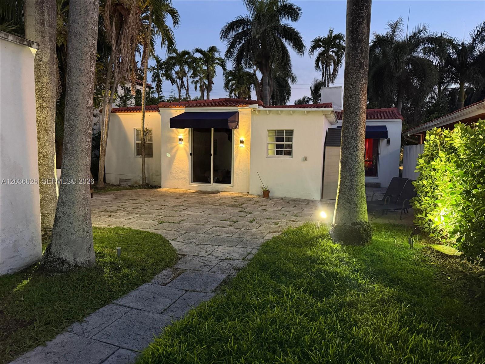 A paved patio leads to the exterior of a white house with palm trees — 265-A Palm Ave, Miami Beach FL 33139, MIAMI BEACH, FL