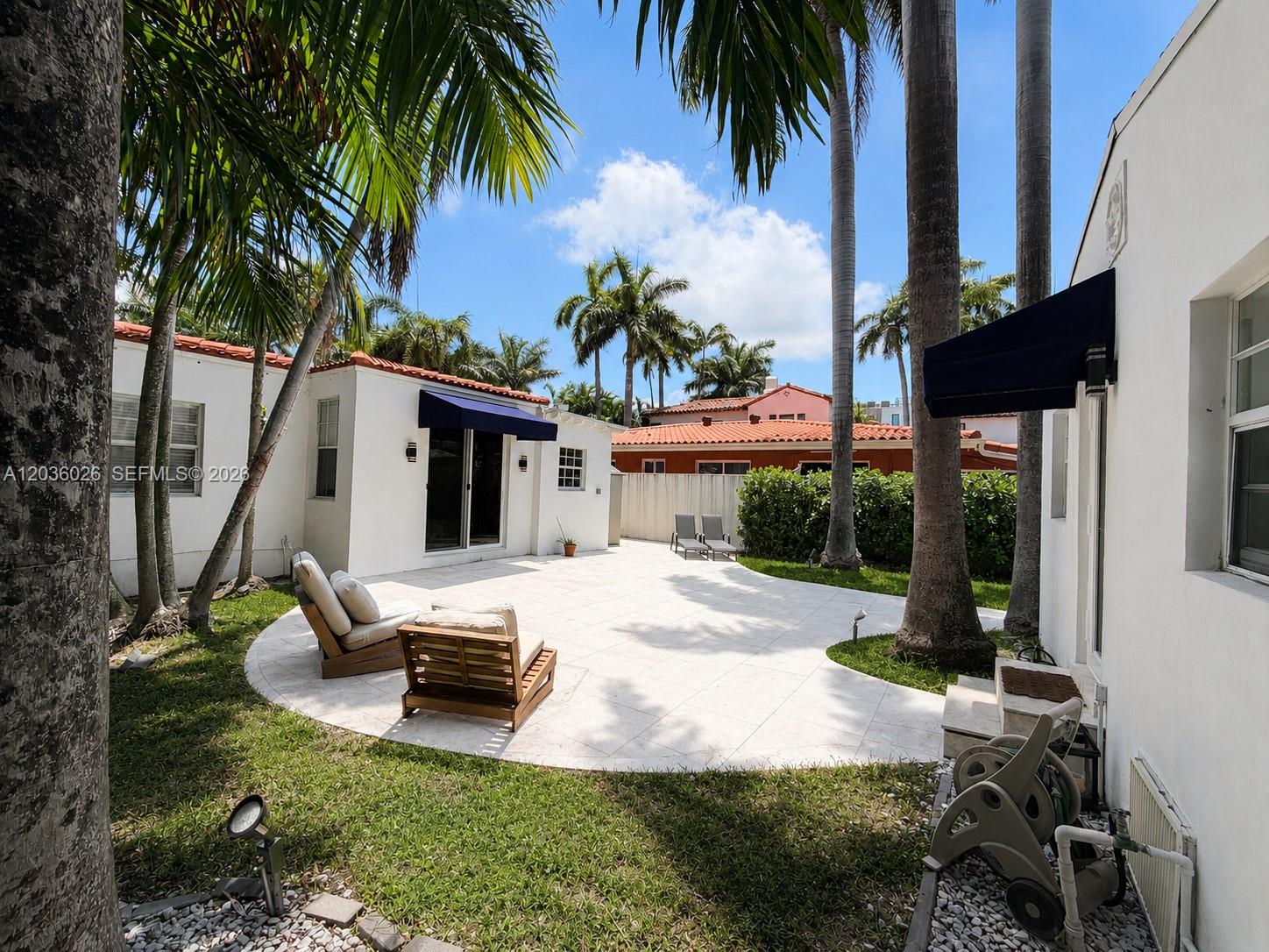 A white patio with lounge chairs sits between two white buildings under palm trees — 265-A Palm Ave, Miami Beach FL 33139, MIAMI BEACH, FL