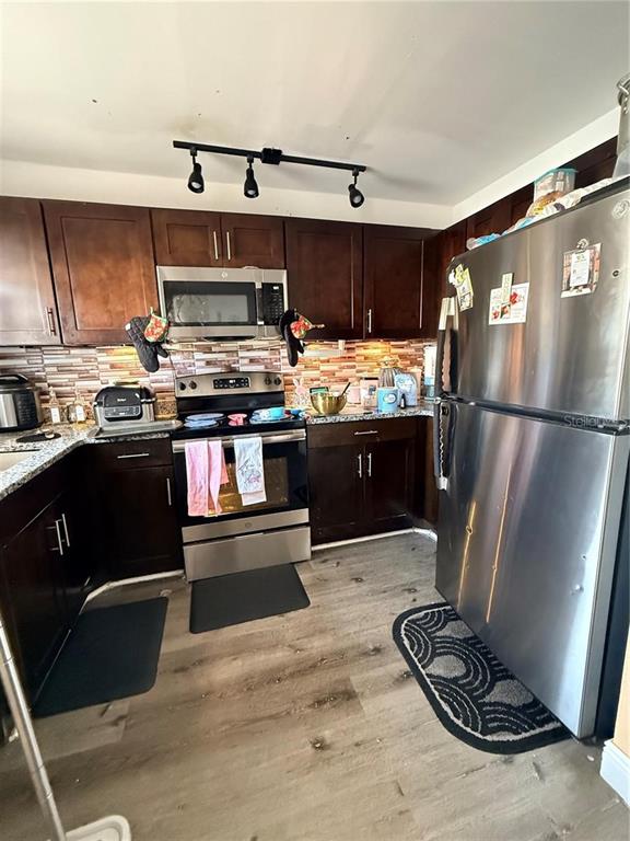 A kitchen features dark wood cabinets, stainless steel appliances, and a tiled backsplash — 1805 MICHIGAN AVENUE UNIT D, KISSIMMEE, FL