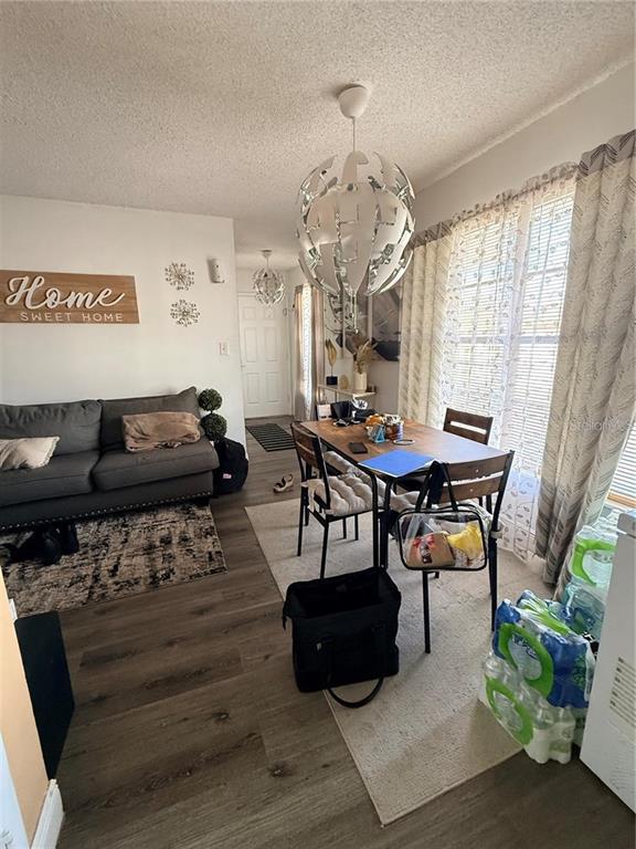 A living and dining area features wood-look flooring, a gray sofa, and modern pendant lighting — 1805 MICHIGAN AVENUE UNIT D, KISSIMMEE, FL