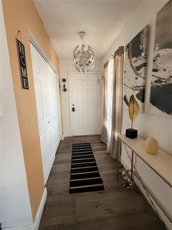 An entryway features wood-look flooring, a white door, a modern chandelier, and a console table — 1805 MICHIGAN AVENUE UNIT D, KISSIMMEE, FL