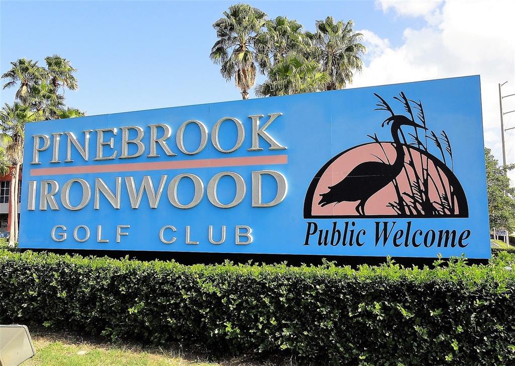 A blue sign for Pinebrook Ironwood Golf Club stands behind a manicured green hedge — 4240 IRONWOOD CIRCLE UNIT 406AA, BRADENTON, FL