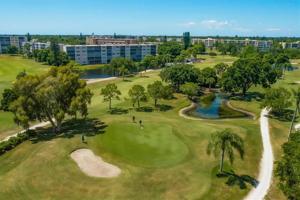 An aerial view of a golf course green with a sand bunker and nearby buildings — 4240 IRONWOOD CIRCLE UNIT 406AA, BRADENTON, FL