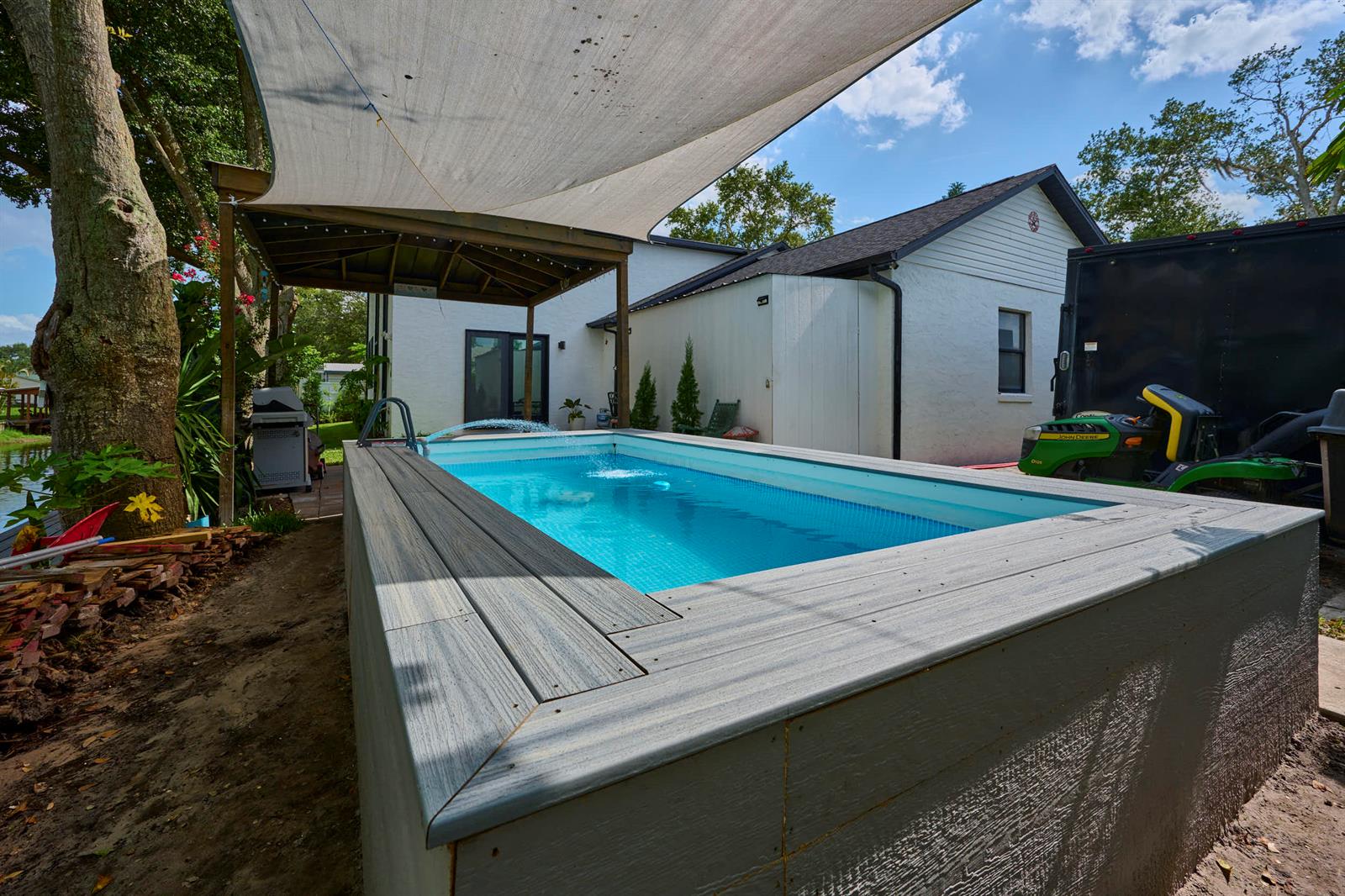 An above-ground rectangular pool with a grey composite deck sits under a shade sail — 441 Spoonbill Court, FL 34739, FL
