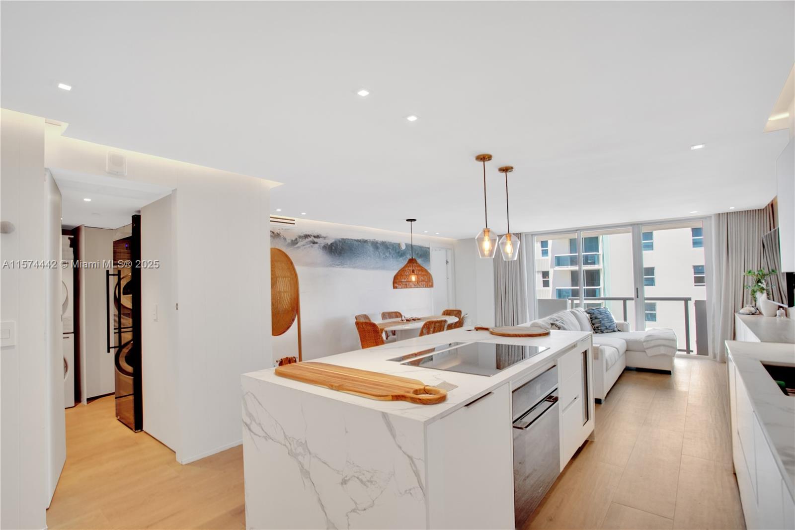 A modern kitchen with a marble island and dining area opens to a living room — 9195 Collins Ave # 903, Surfside FL 33154, SURFSIDE, FL
