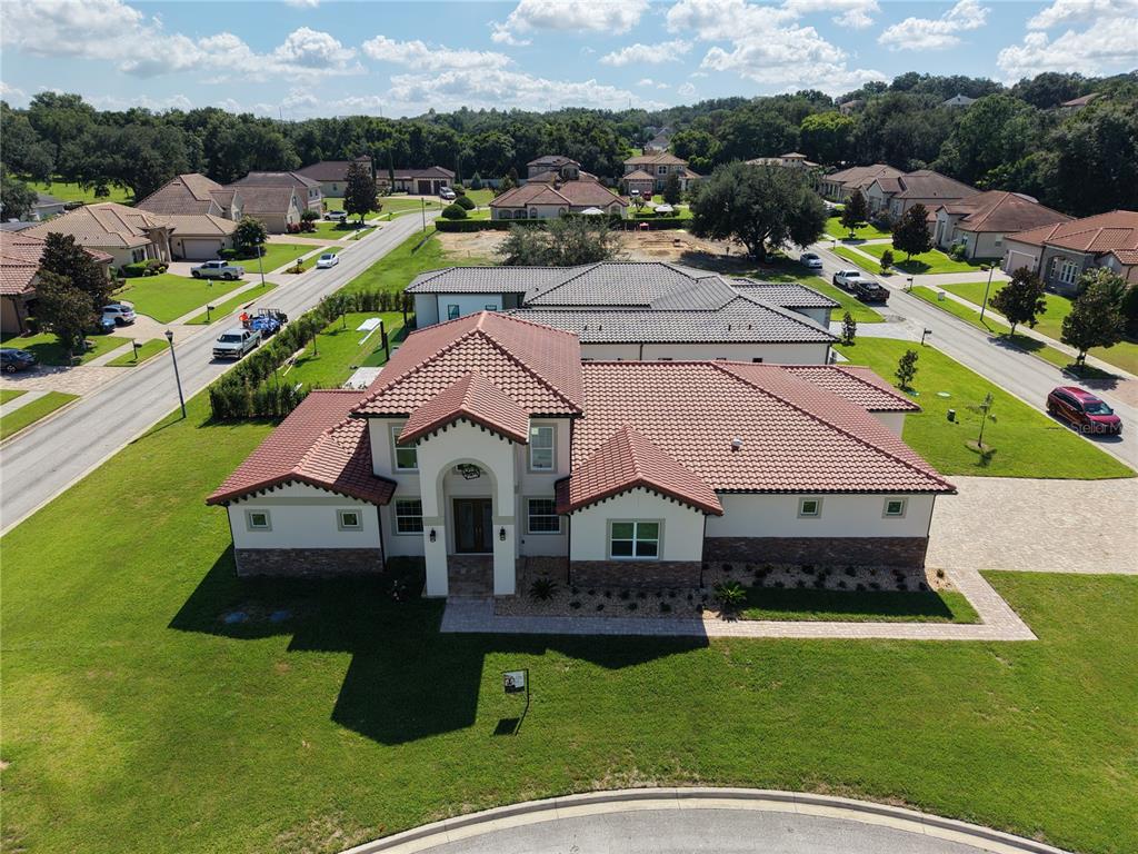 An aerial view shows a two-story house with a red tile roof and a paved driveway — 12926 BRUNELLO CIRCLE, CLERMONT, FL