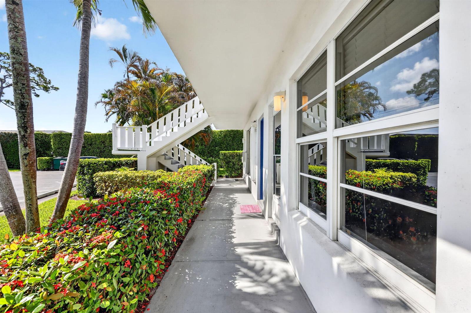 A concrete walkway runs alongside a white building with large windows and a staircase — 2929 SE Ocean Boulevard # M4, Stuart FL 34996, STUART, FL