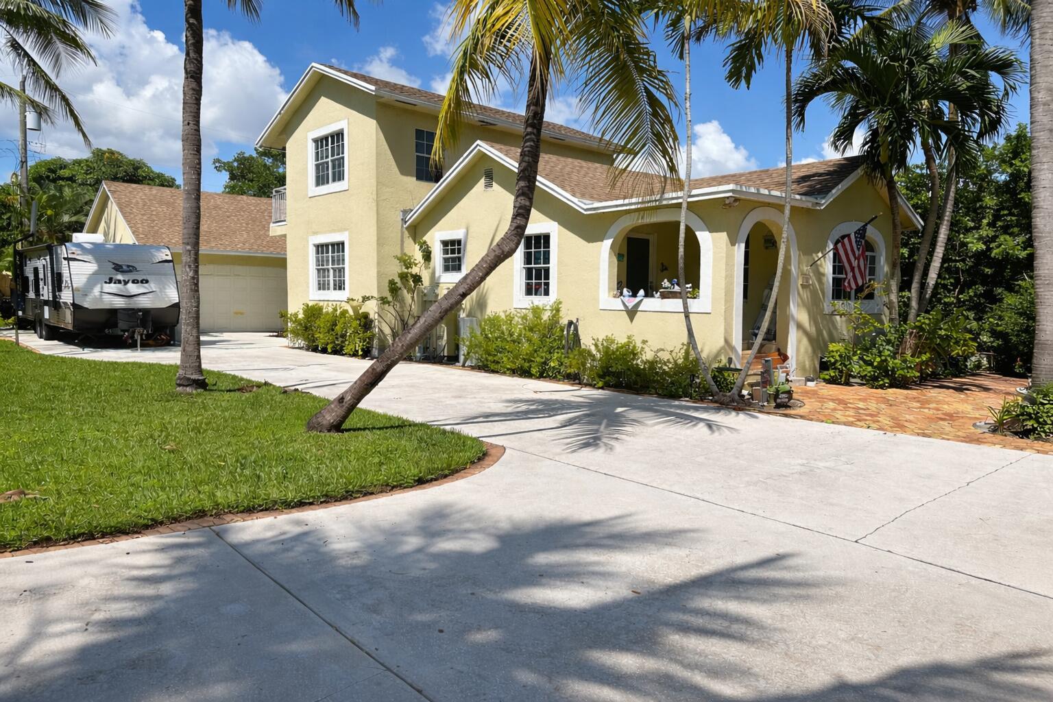 A yellow two-story house with a concrete driveway, a parked RV, and several palm trees — 613 N 5th Street, Lantana FL 33462, LANTANA, FL
