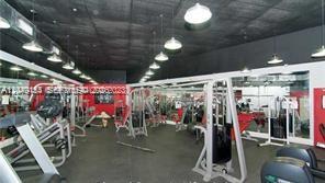A gym interior features various weight training machines, mirrored walls, and industrial-style pendant lighting — 5445 Collins Ave # 721, Miami Beach FL 33140, MIAMI BEACH, FL