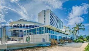 A modern multi-story building with glass windows and a palm tree under a blue sky — 5445 Collins Ave # 721, Miami Beach FL 33140, MIAMI BEACH, FL