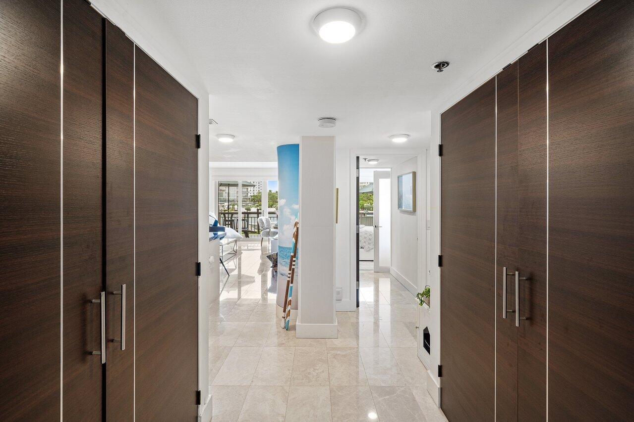 A hallway with dark wood cabinets on both sides leads to a bright living area — 901 E Camino Real # 1c, Boca Raton FL 33432, BOCA RATON, FL