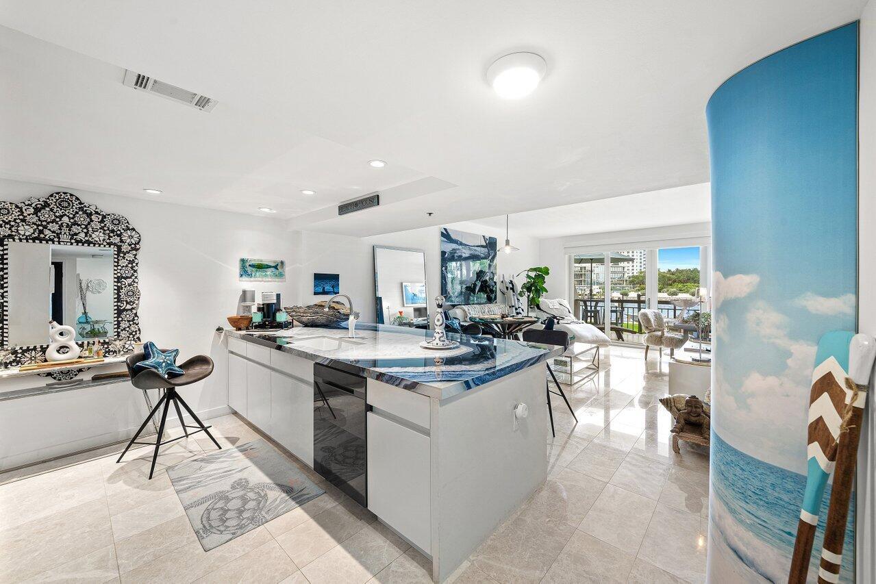 A kitchen with a blue-patterned island countertop, white cabinetry, and a view of a balcony — 901 E Camino Real # 1c, Boca Raton FL 33432, BOCA RATON, FL