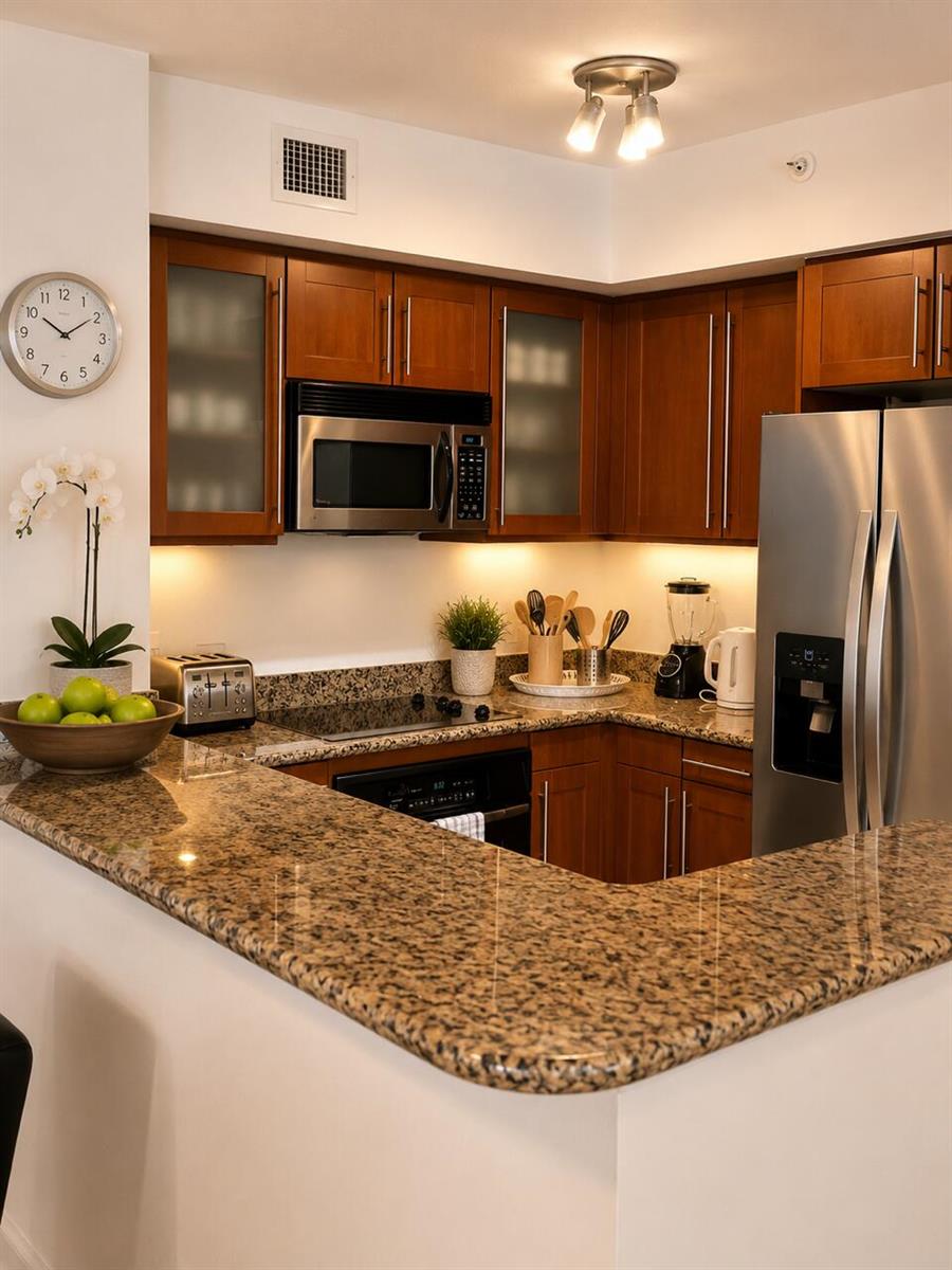 A kitchen features wood cabinets, granite countertops, stainless steel appliances, and under-cabinet lighting — 2080 S Ocean Drive # 505, Hallandale Beach FL 33009, HALLANDALE BEACH, FL