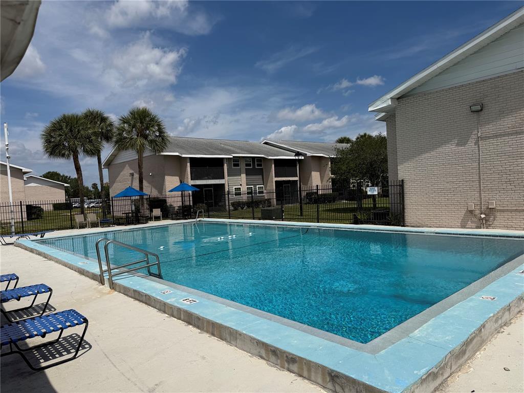 An outdoor swimming pool is surrounded by a concrete deck, lounge chairs, and apartment buildings — 843 SKY LAKE CIRCLE UNIT D, ORLANDO, FL