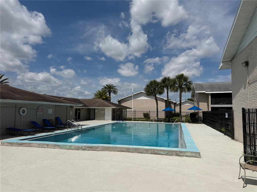 An outdoor rectangular swimming pool is surrounded by a concrete deck and apartment buildings — 843 SKY LAKE CIRCLE UNIT D, ORLANDO, FL