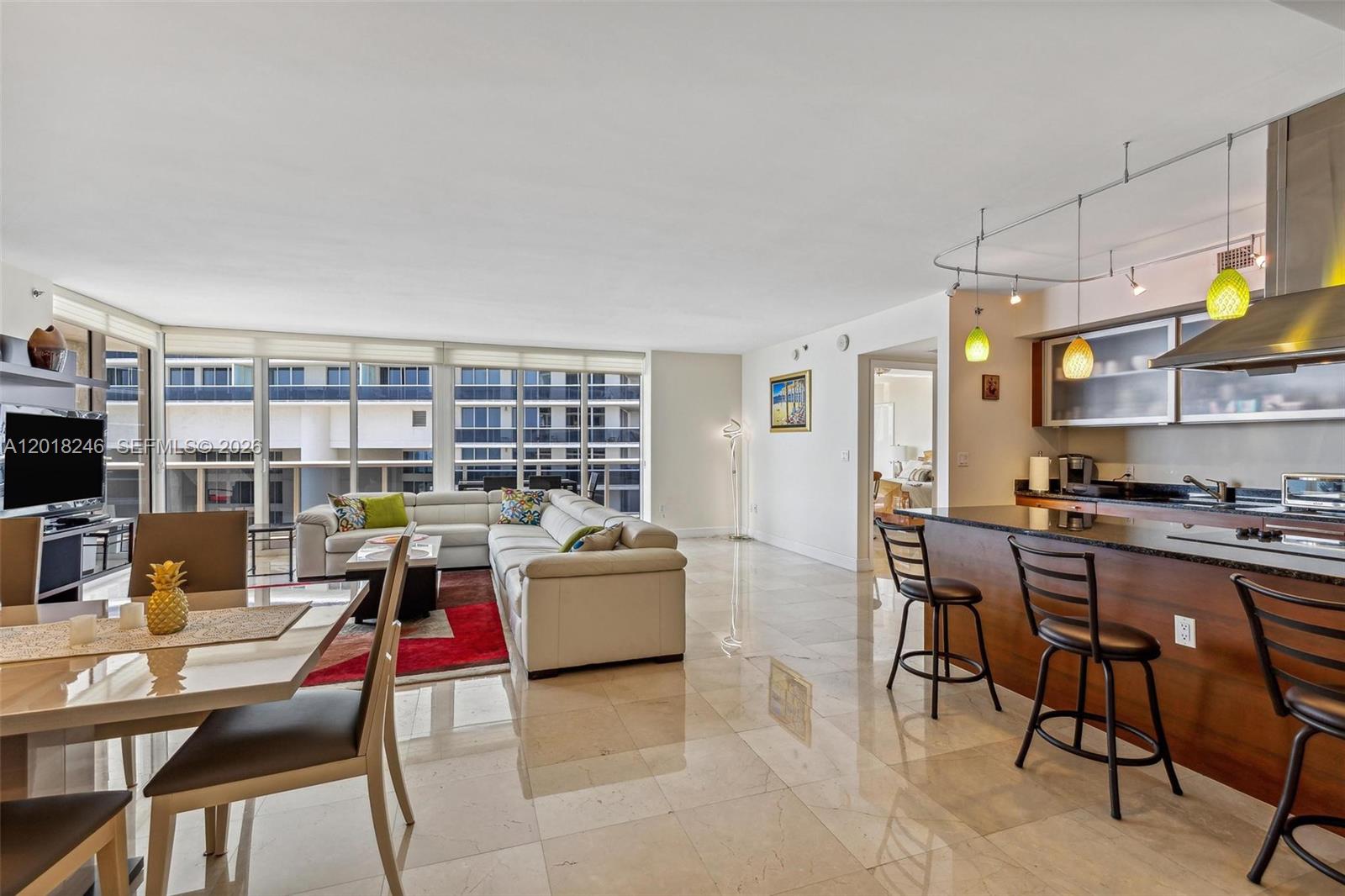 An open-concept living and dining area features marble floors, a kitchen island, and floor-to-ceiling windows — 1800 S Ocean Dr # 1005, Hallandale Beach FL 33009, HALLANDALE BEACH, FL